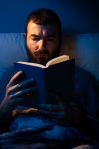 Young man holding camera on bed