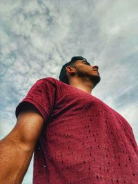 Low angle view of young man looking away against sky