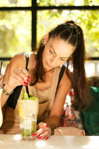 Young and pretty girl, shaking a freshly made mojito