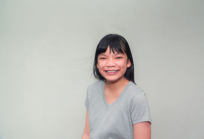 Portrait of smiling young man standing against wall