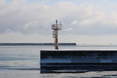 Lighthouse by sea against sky