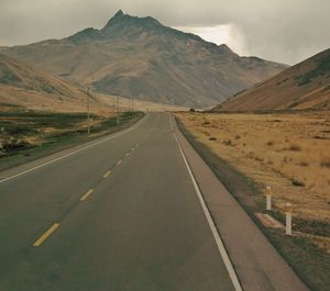 Road leading towards mountains against sky