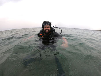 Portrait of happy man swimming in sea against sky