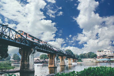 Arch bridge over river against cloudy sky