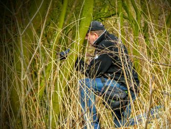 Man photographing with camera while sitting amidst grassy field