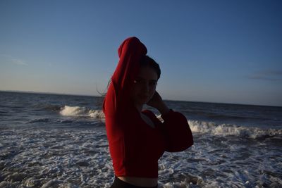 Rear view of woman standing at beach against sky