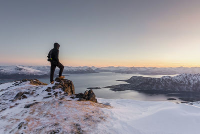 Man standing on snowcapped mountain against sky during winter
