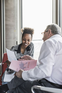 Senior manager discussing documents with young coworker