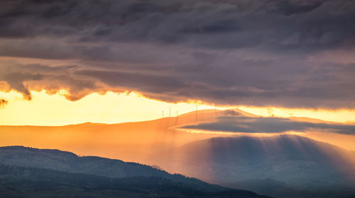 Scenic view of mountains against dramatic sky during sunset