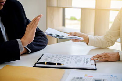 Businesswoman giving bribe to sign contract on table