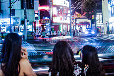 Rear view of woman walking on road in city at night