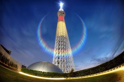 Low angle view of illuminated tower against blue sky