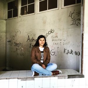 Portrait of young woman sitting on wall