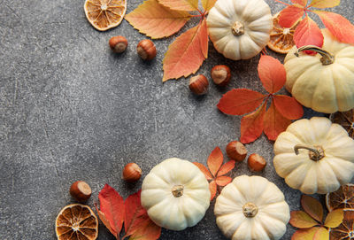 Thanksgiving season still life with small pumpkins and fall leaves over grey concrete background