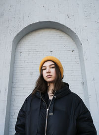 Teen girl in a knitted hat on the street against the wall