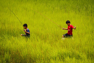 Full length of men fishing in grass