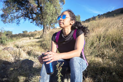 Young woman wearing sunglasses on field during sunny day