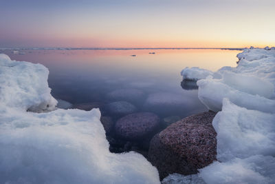 Frozen sea against sky during sunset