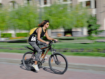 Side view of young woman riding bicycle on road