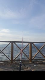 Metal railing by sea against sky
