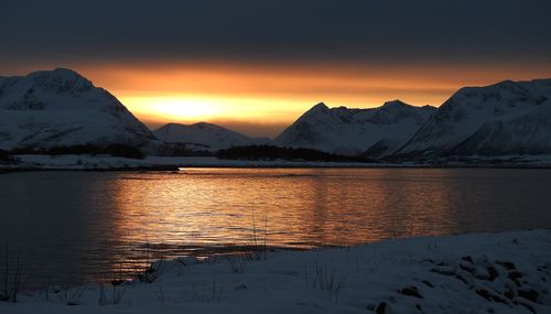 Scenic view of lake and mountains against sky during sunset