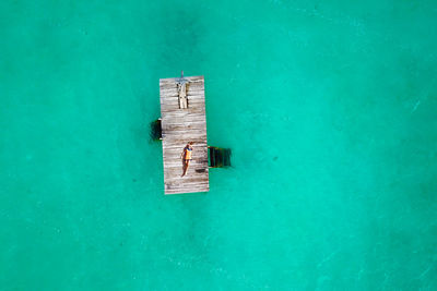 Aerial view of woman lying on pier in sea