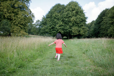 Rear view of girl running on field