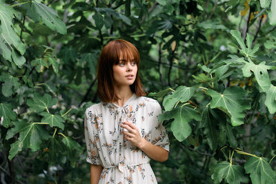 Portrait of young woman standing against plants