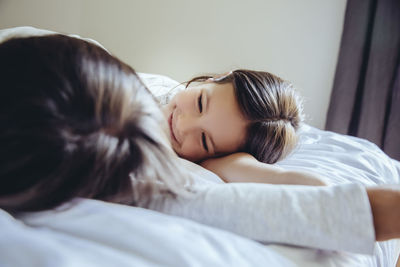 Mother and daughter cuddling on bed