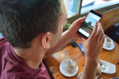 High angle view of man using phone at cafe