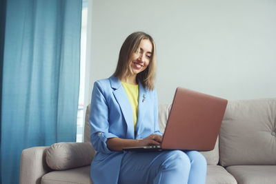 Smiling businesswoman working in laptop sitting on sofa