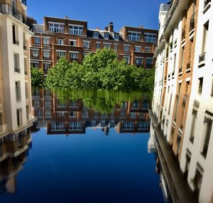 Canal by buildings against sky