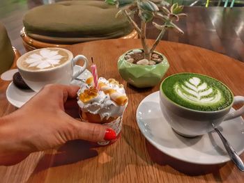 Close-up of hand holding drink served on table