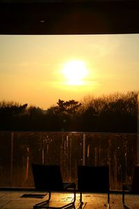 Chairs and table in balcony against sea during sunset