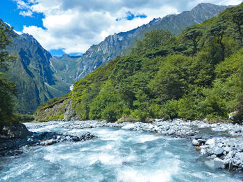 Scenic view of river amidst mountains against sky