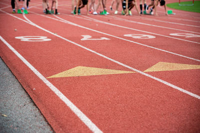 Runners at the starting line on blocks at an athletic racing track with numbers and lane markings