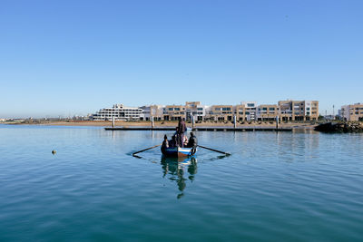People on boat in water against clear sky