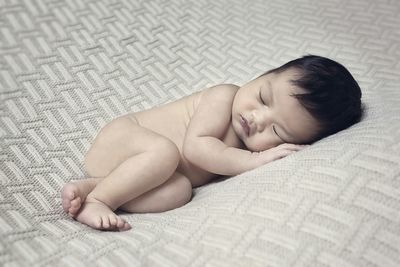 Cute naked baby sleeping on bed