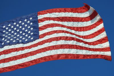 Low angle view of flag against clear blue sky