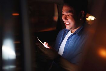 Smiling man using mobile phone at night