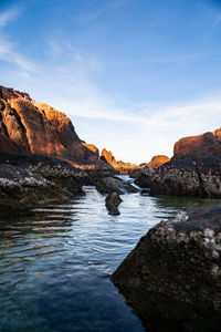 Rock formations in water against sky