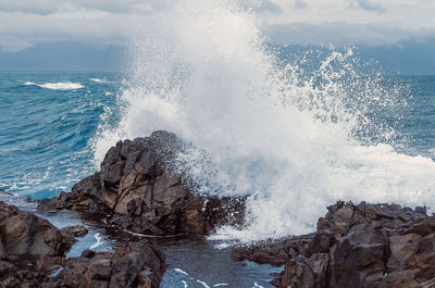 Aerial view of waves splashing on rock