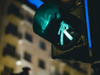 Low angle view of illuminated road sign against sky at night