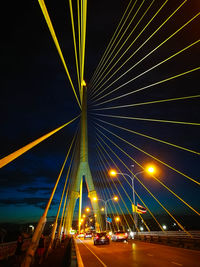Road passing through illuminated bridge at night