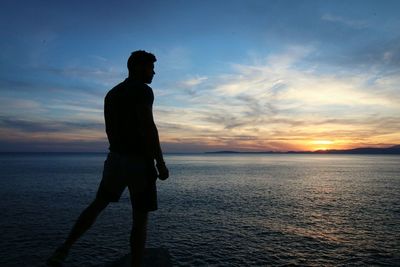 Silhouette man standing on beach against sky during sunset