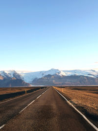 Empty road against clear blue sky