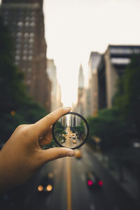 Close-up of hand holding lens against blurred background