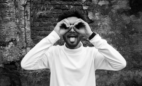 Portrait of man making funny face while standing against wall