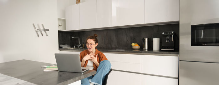 Portrait of young woman using digital tablet while sitting on table