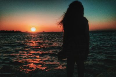 Woman standing at beach during sunset